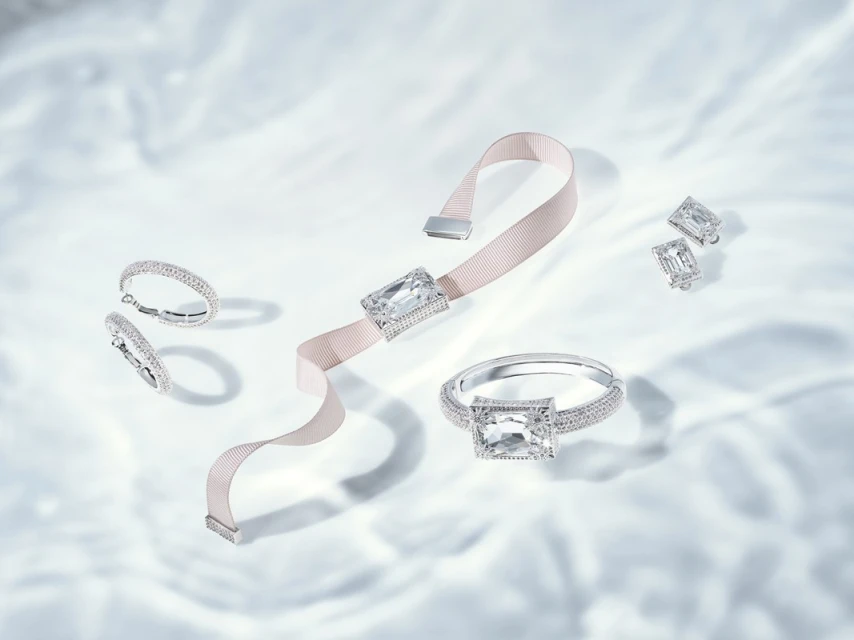 Elegant jewellery set featuring a bracelet, ring, and earrings with large, clear gemstones on a light, rippled background. 