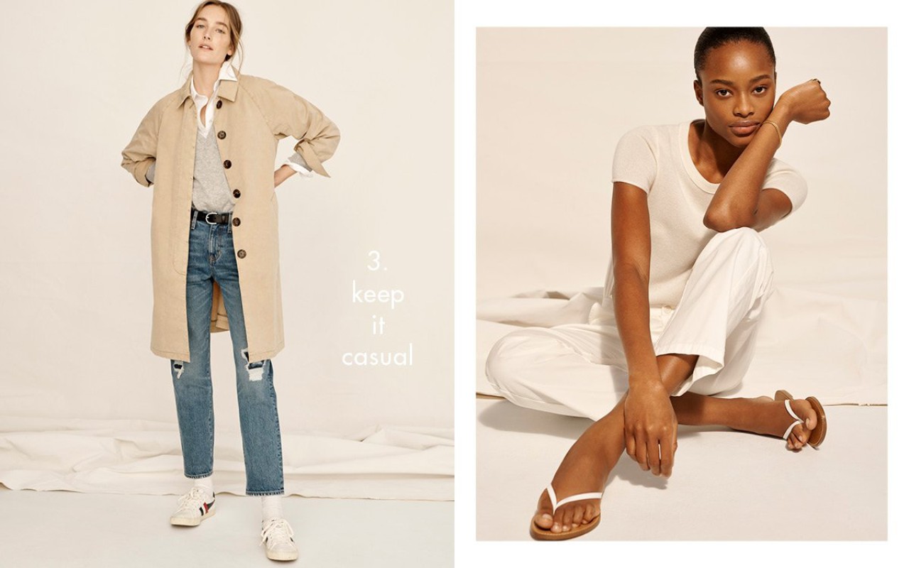 Two women pose in casual outfits against a bright backdrop. One wears a tan trench coat, jeans, and sneakers; the other wears white clothing.