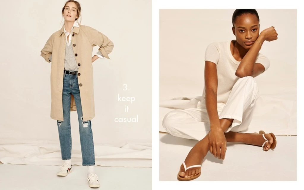 Two women pose in casual outfits against a bright backdrop. One wears a tan trench coat, jeans, and sneakers; the other wears white clothing.