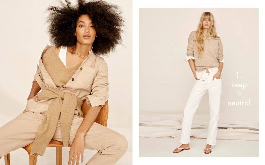 Two women pose indoors in neutral-toned, casual fashion. One wears a tan jumpsuit and the other a beige sweater with white jeans.