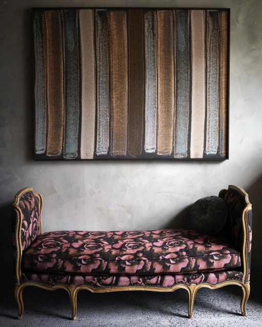 Interior design featuring a floral settee in front of an abstract painting with gray concrete wall providing a modern contrast.