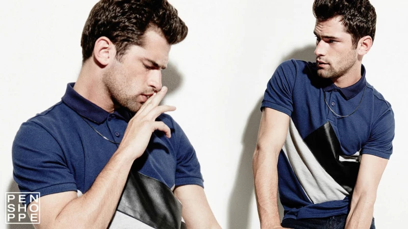 Studio shot of a handsome adult male in a blue polo shirt with a modern design element, captured against a bright white backdrop.