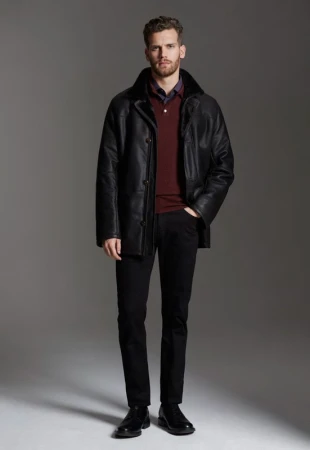 Man wearing a black leather jacket over a burgundy polo shirt and dark trousers against a neutral grey studio background