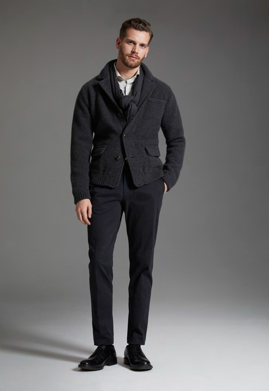 Full-length shot of an adult male wearing a grey jacket, vest, white shirt, dark pants, and black leather shoes, in a studio setting.