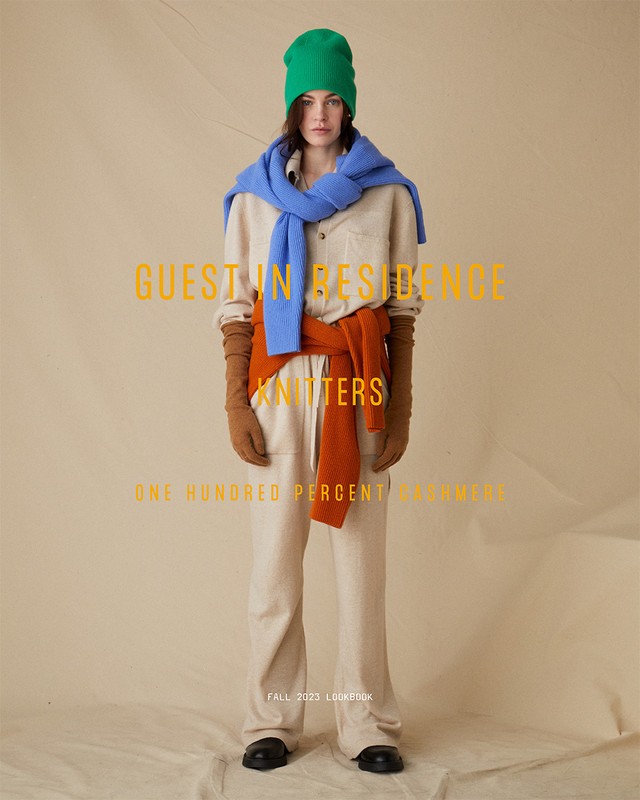 Fashion portrait of a female model wearing a cream-colored jumpsuit, bright green beanie, and a light blue scarf against beige background.