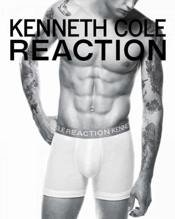 Male model torso shot in underwear, tattooed arms, Kenneth Cole Reaction branding, black and white image on a white backdrop.