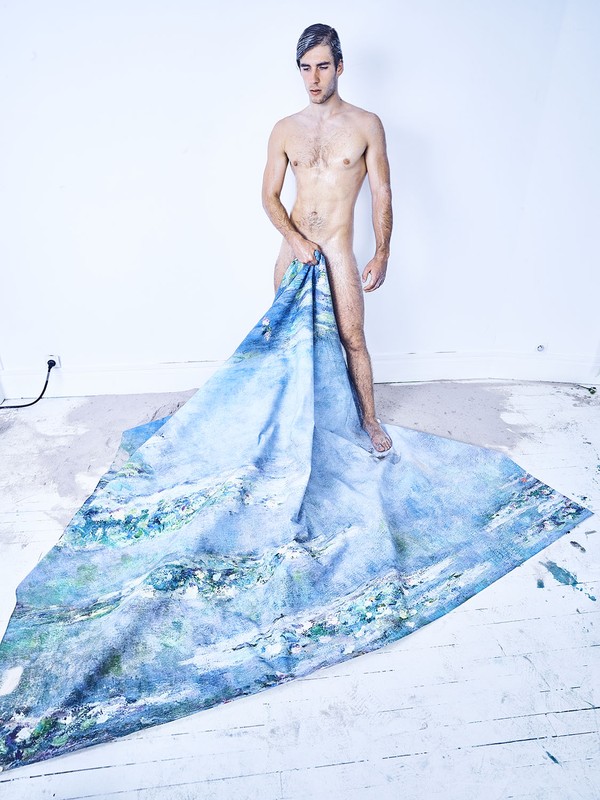 Nude man with silver hair stands in white room holding blue fabric with painterly mountain and water scene, art photography.