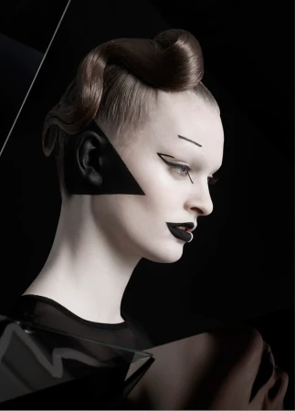 Profile of a woman with stylized makeup and a geometric black design, featuring a sleek updo hairstyle against a dark background.