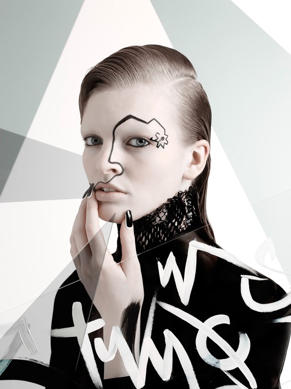 A young adult female model poses with black and white body paint, nail polish, lace collar, and slicked-back hair in front of a geometric background.
