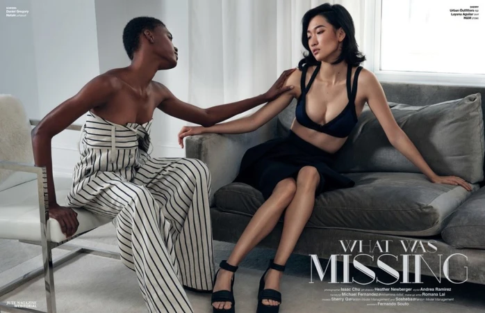 Two fashion models posing together in a bright interior space with minimalist furniture and white sheer curtains.