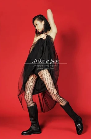 Model in black tulle skirt and patterned tights holding fabric against a solid red background