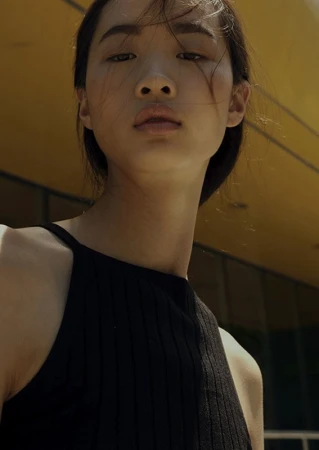 Low angle portrait of an East Asian model wearing a black ribbed tank top with hair styling by Michael J. Fernandez in Los Angeles.