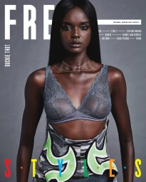 Model Duckie Thot wearing grey lace lingerie and a structured patterned corset against a grey background.