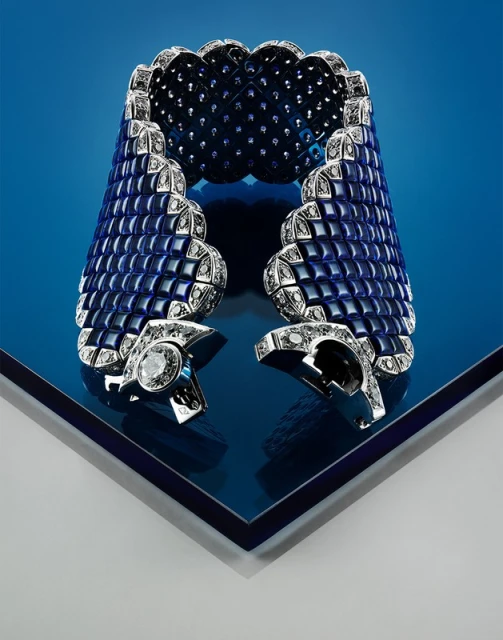 Stunning blue and silver diamond-patterned cuff bracelet on reflective surface. Fine jewelry fashion product shot with luxury design.