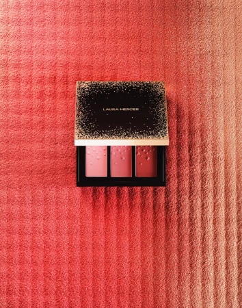 Laura Mercier blush palette on a pink striped towel background, displaying three shades of pink and coral blush colors.
