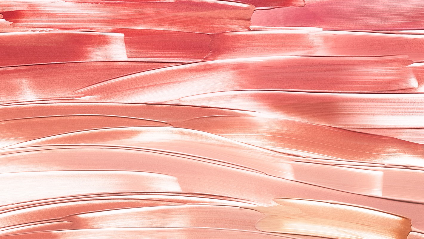 Close-up of cosmetic smears in shades of coral and beige, showcasing a glossy and creamy texture ideal for beauty and makeup visuals.