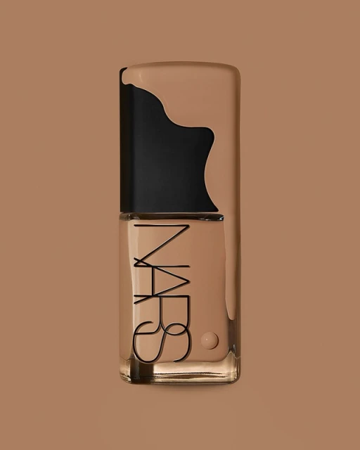 Studio shot of a NARS foundation bottle on a monochromatic tan background, with the brand logo prominently displayed on the glass.