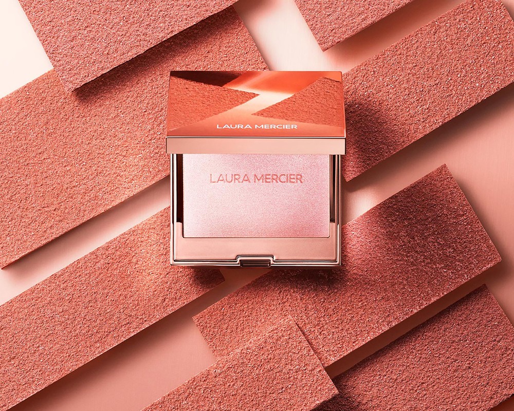 Laura Mercier blush compact on pink background with geometric accents, showcasing makeup, beauty product, and cosmetics.
