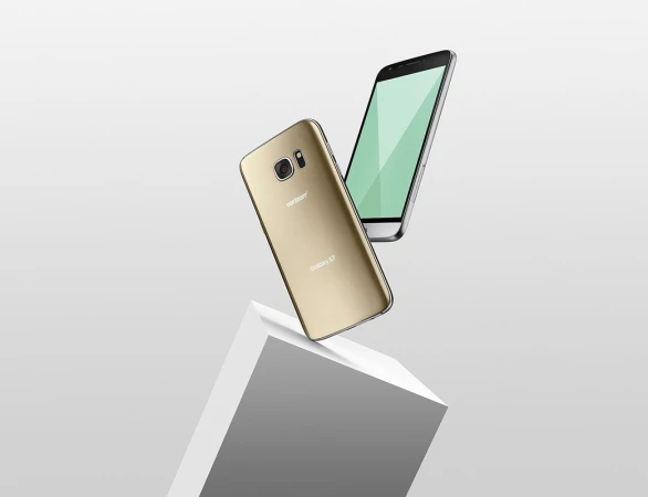 Two smartphones, one gold and one silver, float in a studio-lit scene, positioned above a white geometric block against a gradient background.