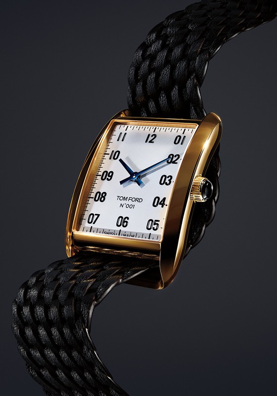 Elegant rectangular gold watch on a woven black leather strap, against a dark gray backdrop, showcasing luxury timekeeping and design.