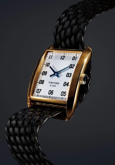 Elegant rectangular gold watch on a woven black leather strap, against a dark gray backdrop, showcasing luxury timekeeping and design.