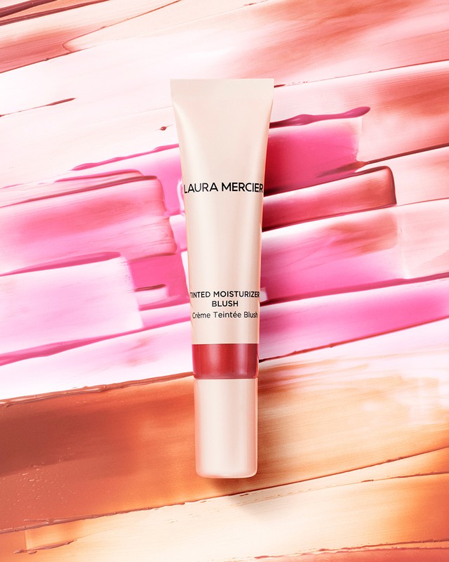 Laura Mercier tinted moisturizer blush tube on a pink and peach colored, textured surface, beauty, makeup, and cosmetics.