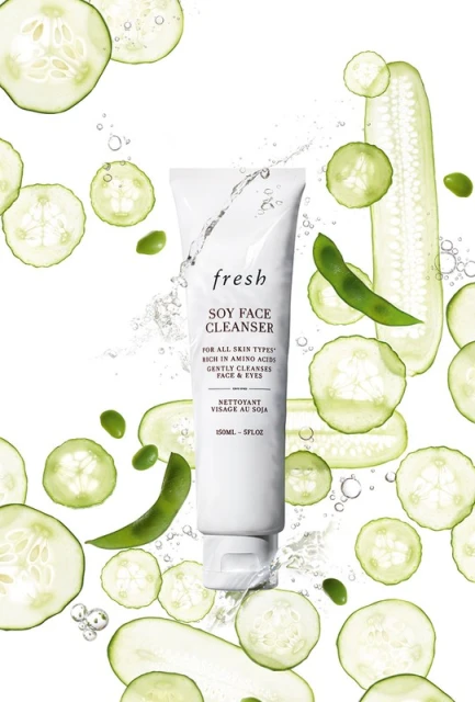 Fresh Soy Face Cleanser tube surrounded by sliced cucumbers and soybeans on a white background for a beauty and skincare product shoot.