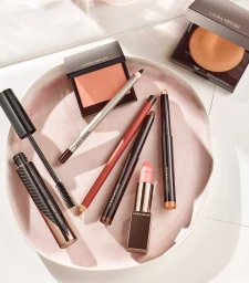 Flat lay of makeup products arranged on a pale pink ceramic dish, styled by Michele Faro in Los Angeles.
