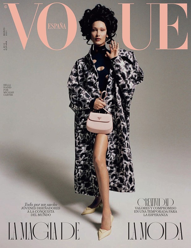 Vogue España cover featuring Bella Hadid in a black and white coat, holding a light pink Prada purse, and wearing nude heels against a gray backdrop.