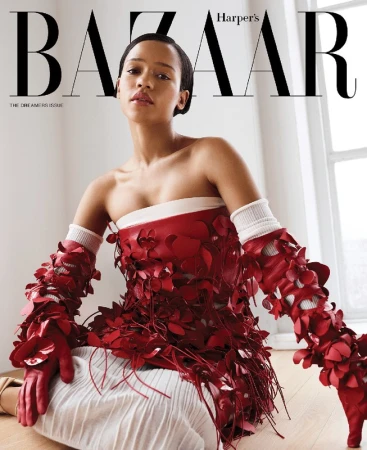 A woman wearing a red floral applique top and long red gloves seated indoors with natural window light