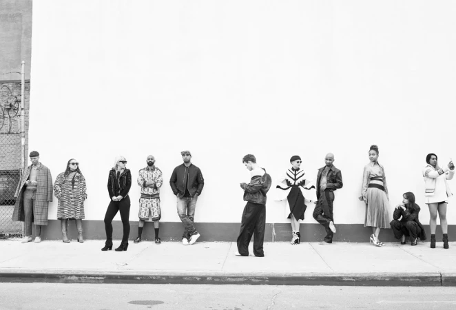 A line of diverse models in varied contemporary street fashion posing against a plain exterior wall in Los Angeles.