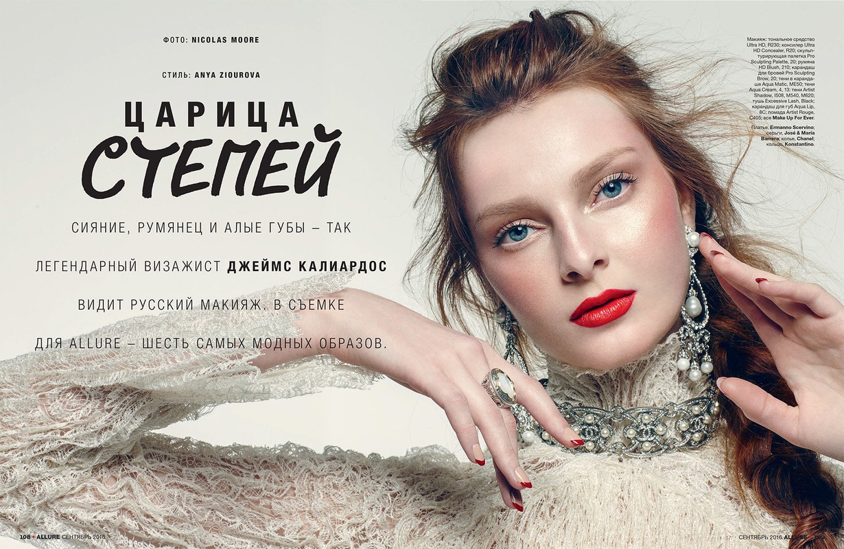 Close-up beauty editorial portrait of a woman with red lipstick, ornate pearl earrings, lace dress, and manicure against white