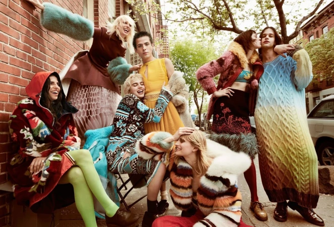 Group of young people in colorful outerwear posing outdoors, brick building background, fashion editorial style, diverse, vibrant clothing.