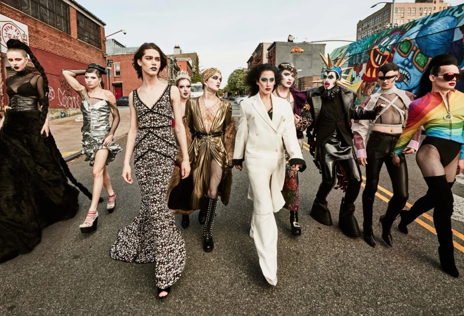 Group of diverse people in fashionable outfits walking on city street with colorful graffiti art, brick buildings, and asphalt road.