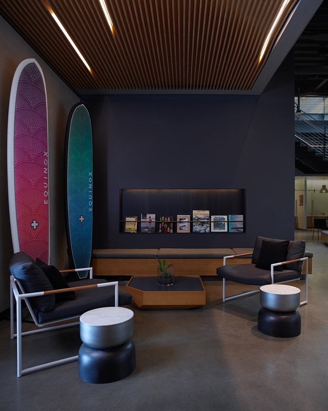 Modern waiting area with surfboards, armchairs, coffee tables, and indirect lighting creates a calm and stylish interior space.