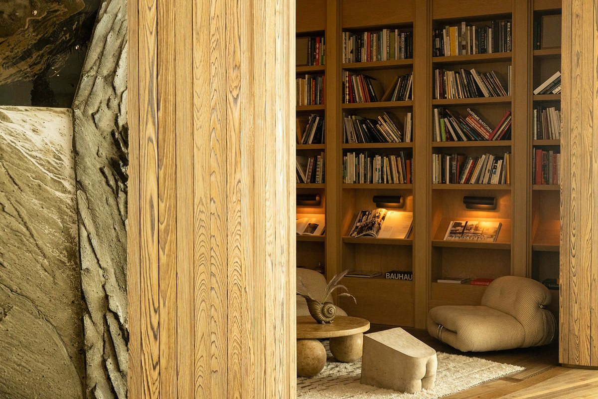 Reading nook with a bookcase and comfortable seating in a warm, inviting space with textured walls and a unique wooden post.