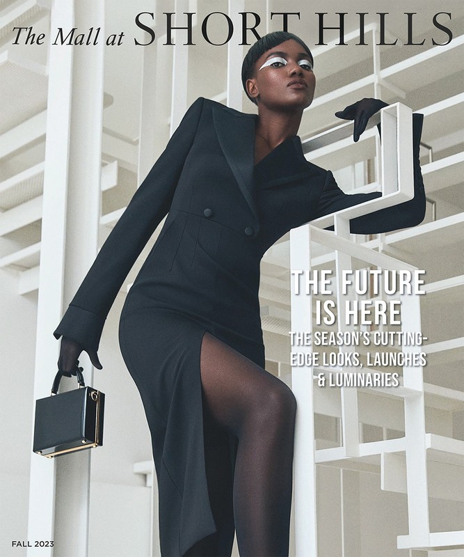 Fashion magazine cover featuring a Black female model in a black dress with a slit, black tights, gloves, and a black purse.