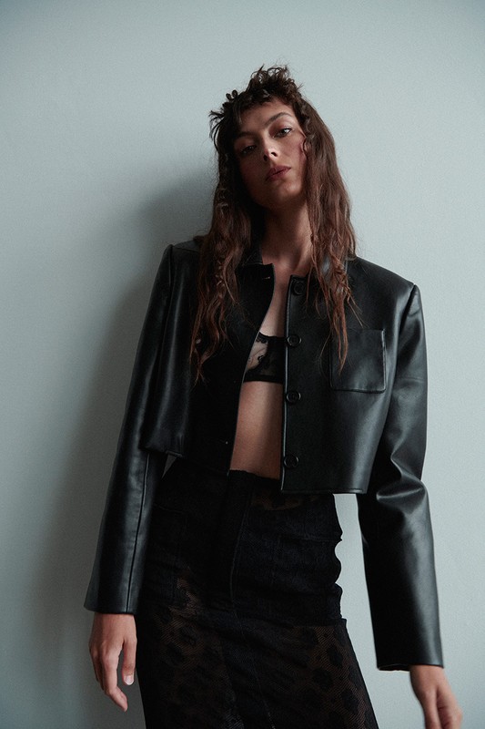 Model wearing a black leather jacket and patterned skirt against a plain light wall, styled by Misuzu Miyake in Los Angeles.