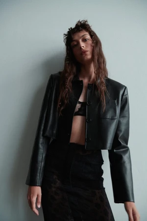 Model wearing a black leather jacket and patterned skirt against a plain light wall, styled by Misuzu Miyake in Los Angeles.