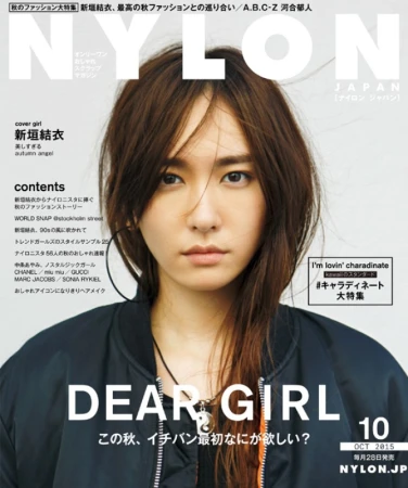 Portrait of a young Japanese woman with dark hair wearing a black bomber jacket against a plain white background for Nylon Japan.
