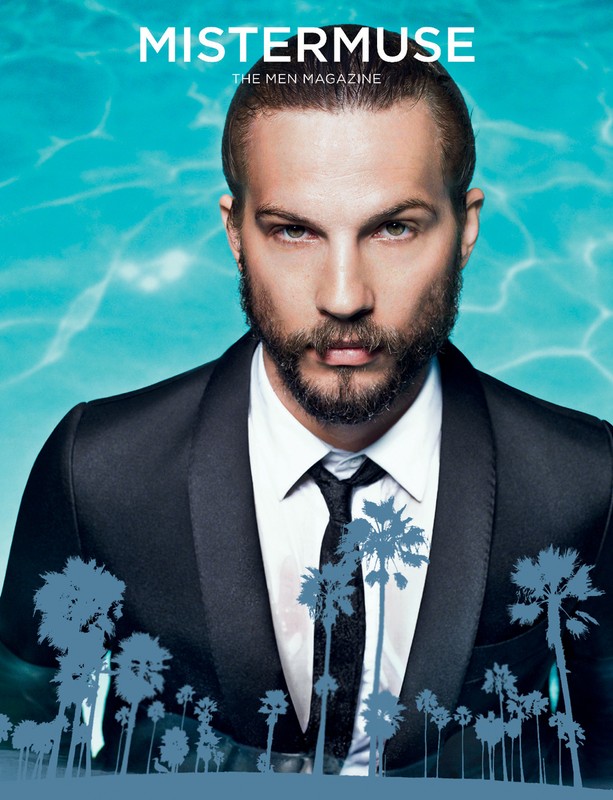 Magazine cover featuring a bearded man in a suit and tie against a blue background with palm tree silhouettes.