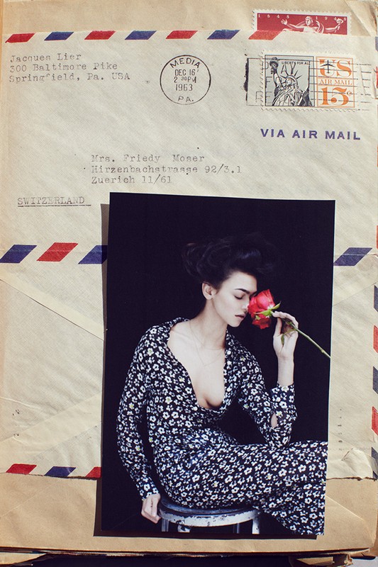 Fashion photo of a woman smelling a red rose, seated on stool, set against vintage envelopes with postage stamps and airmail markings.