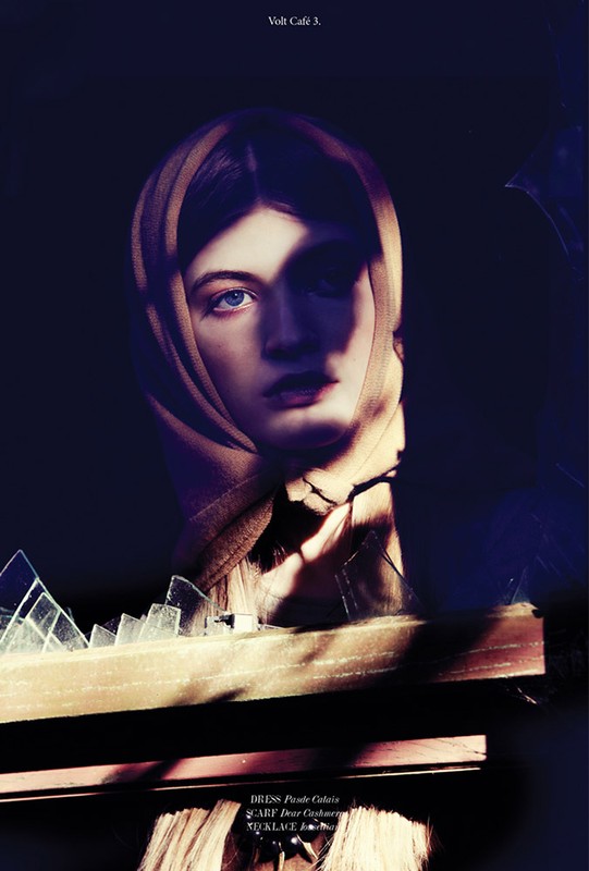 Portrait of a woman wearing a headscarf, framed by shattered glass and a dark background in a high-fashion editorial style.