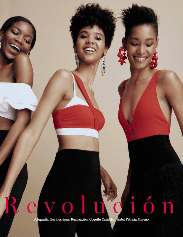 Three smiling Black models wearing red and white tops and black pants pose indoors against a neutral backdrop, fashion editorial style.