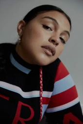 Close-up portrait of a woman wearing a black patterned sweater with red and blue stripes, styled by make-up artist Nancy Sea Siler.
