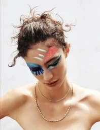 Close-up portrait of a woman with vibrant colorful glitter and painted makeup on her face and eyes.