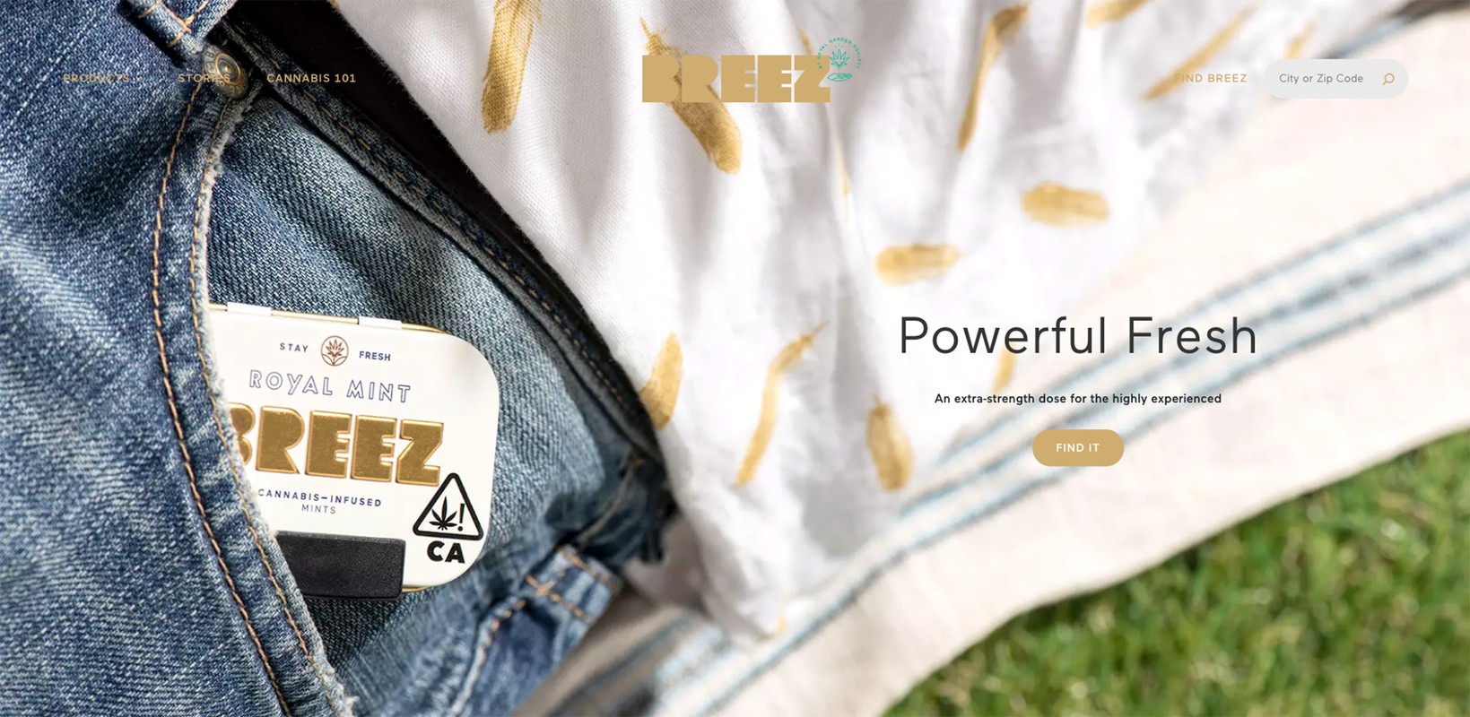 Breez cannabis mints tin in a blue jeans pocket, next to a white and gold patterned cloth, advertisement, product shot.
