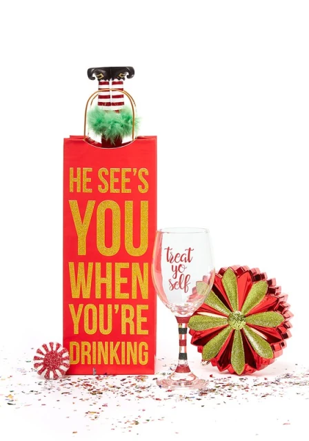 Holiday-themed image featuring a wine glass, a wine bag with text, and decorative ornaments in red, gold, and white against white.