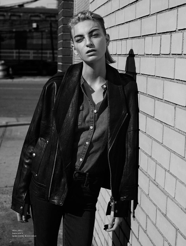 Model in dark leather jacket leaning against a brick wall in black and white photography by Nicolas Eldin