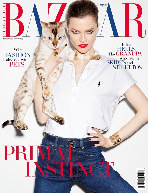 Magazine cover featuring a model with red lipstick holding a cat, with 'BAZAAR' in large red and blue letters at the top.